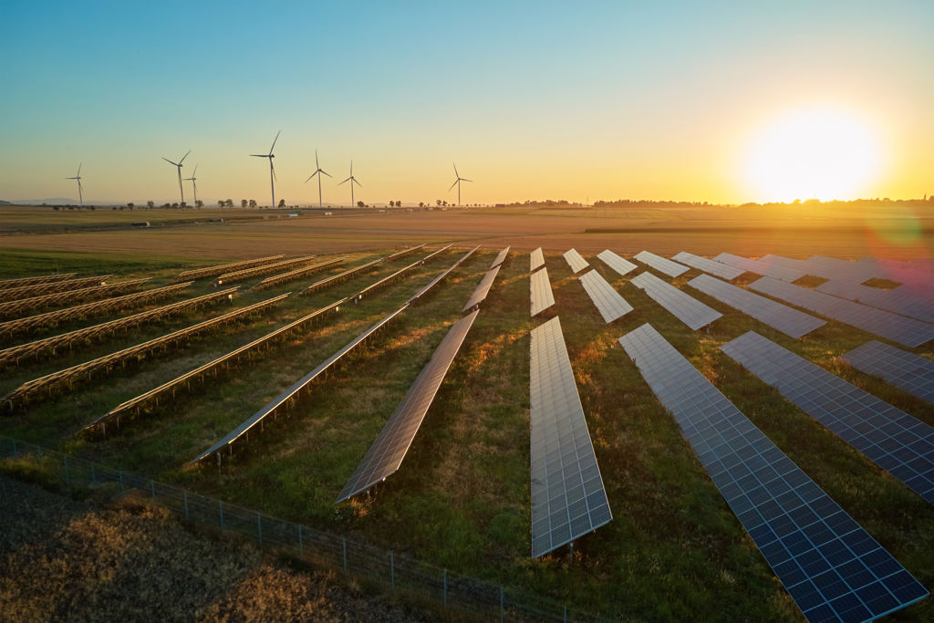 zonnepanelen en windmolens in Nederlands weiland terwijl de zon opkomt